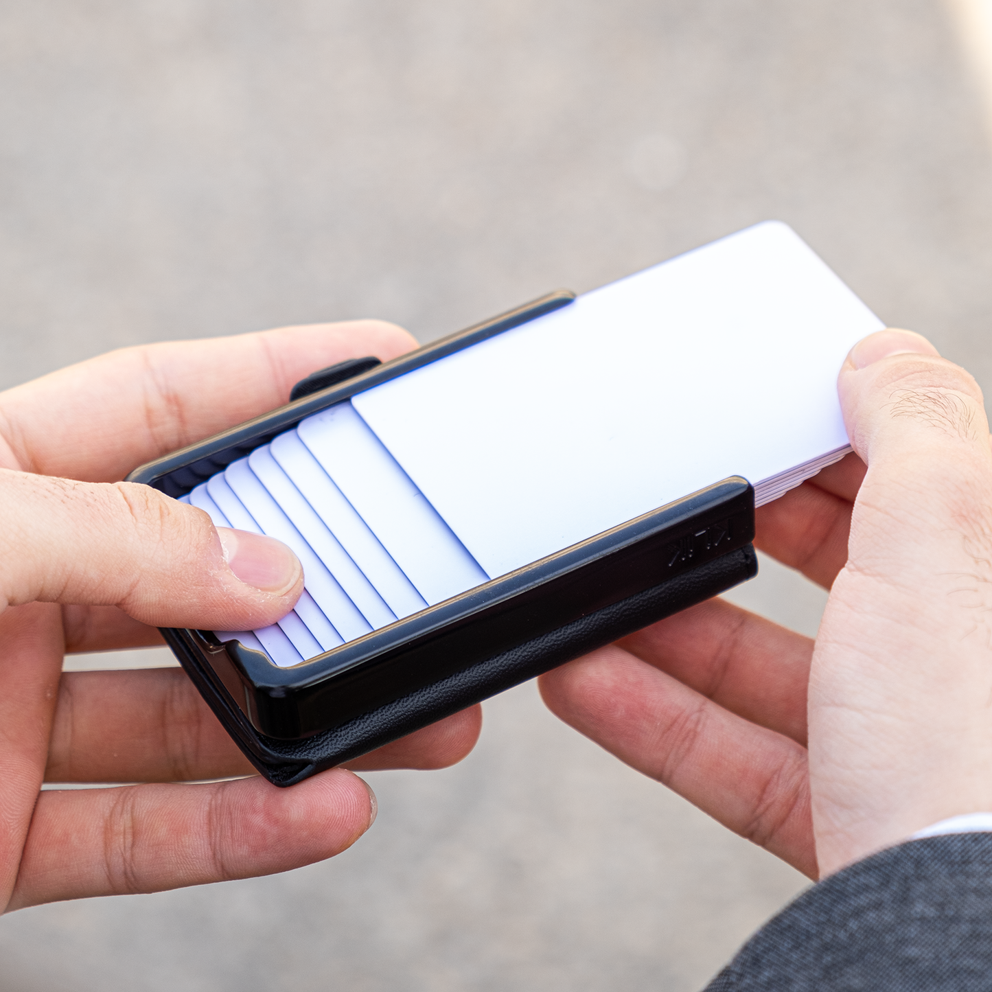 Due mani tengono un portafoglio, con la mano destra sfila una carta bianca. Sfondo chiaro