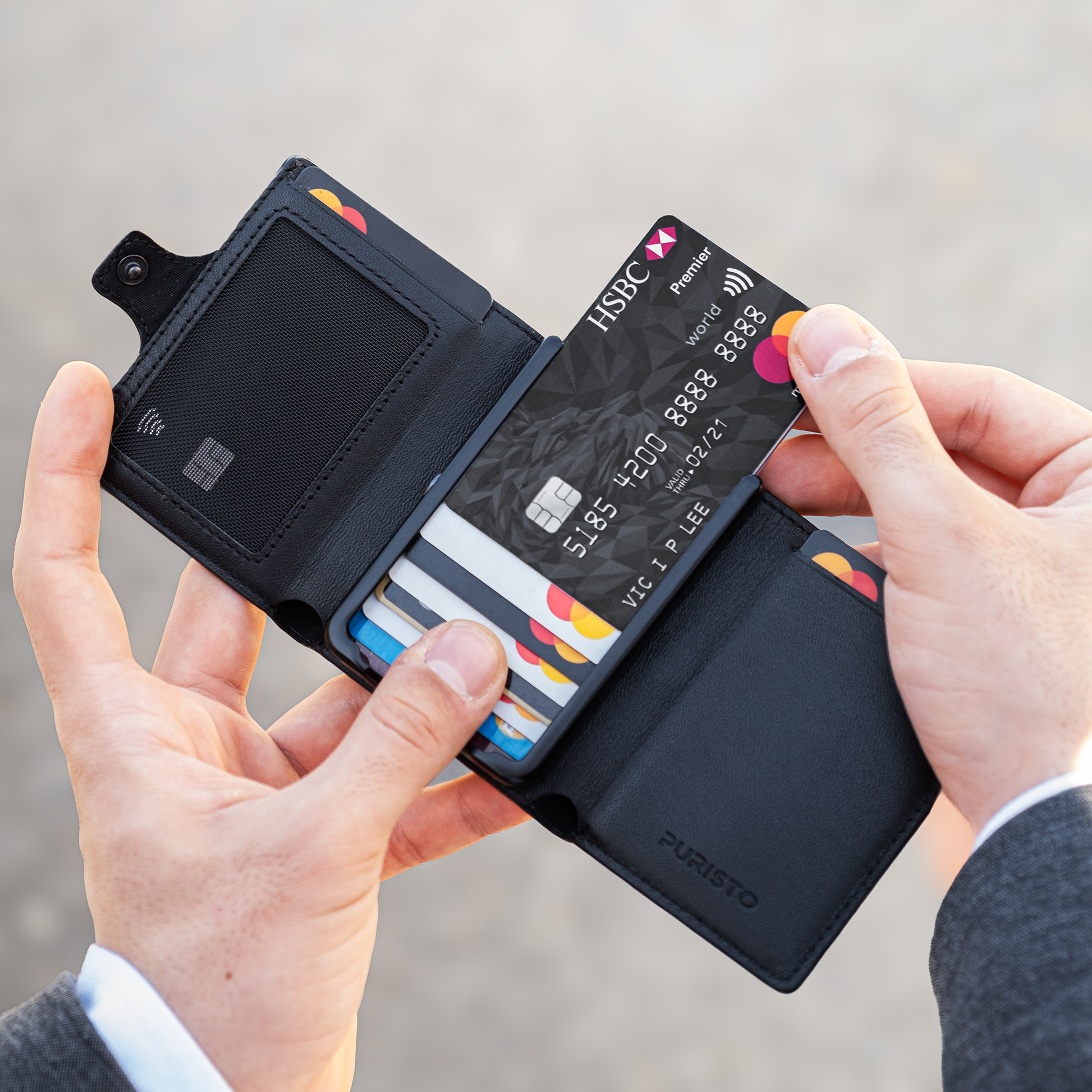 due mani tengono un portafoglio nero con carte di credito, sullo sfondo una superfice chiara