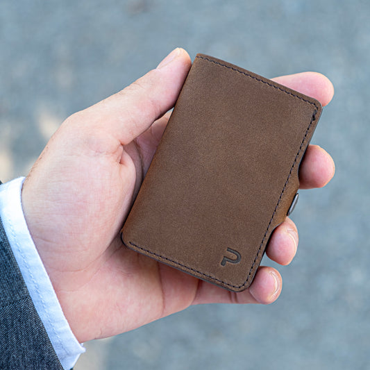 Mano tiene un portafoglio marrone vintage elegante. Sfondo chiaro