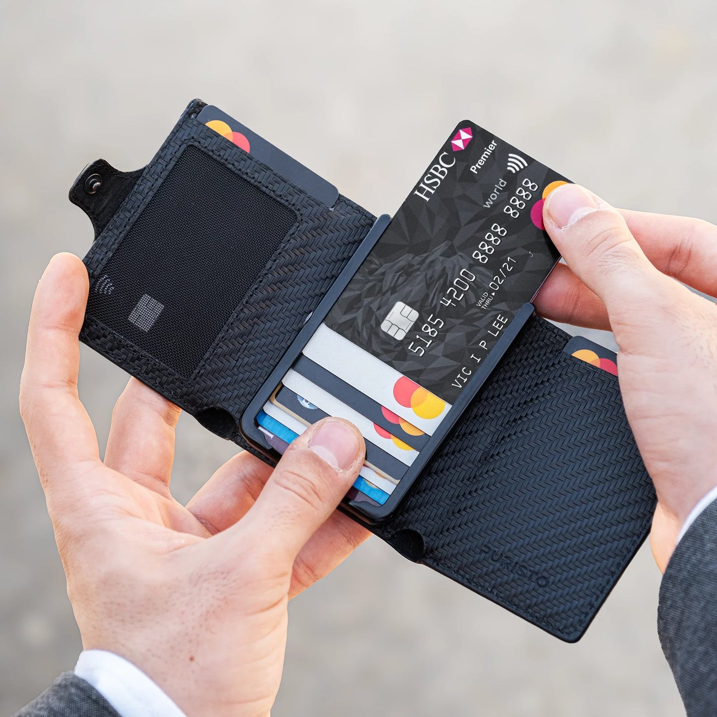 Miniwallet nero compatto con protezione RFID, uomo inserisce carte e banconote.