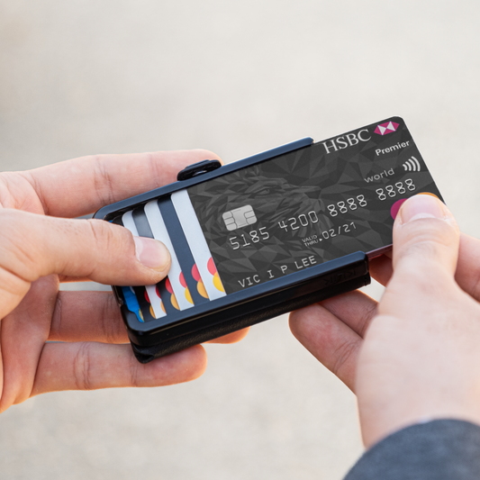 Due mani tengono un portafoglio, con la mano destra sfila una carta di credito. Sfondo chiaro