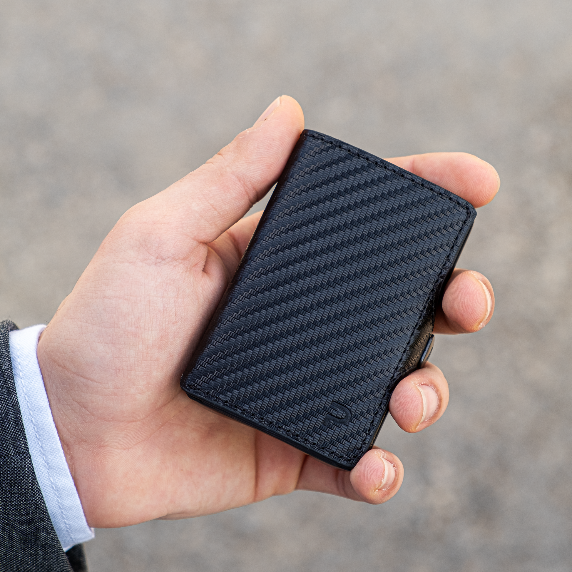 Mano tiene un portafoglio nero in materiale Mirum elegante. Sfondo chiaro