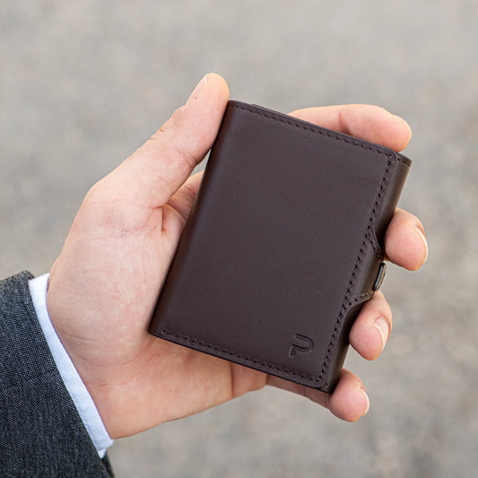 Miniwallet marrone compatto in pelle con protezione RFID tenuto da una mano