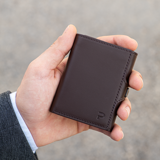 Mano tiene un portafoglio marrone vintage elegante. Sfondo chiaro