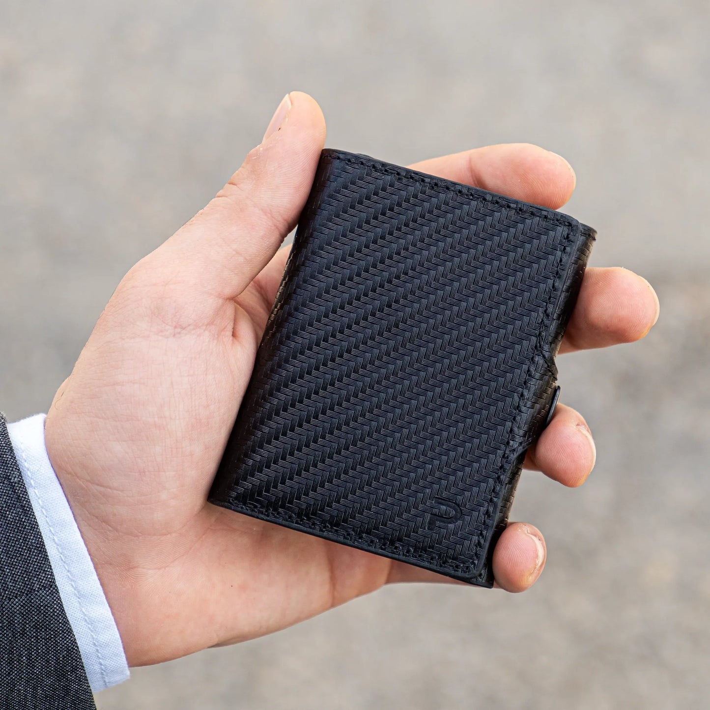 Miniwallet nero compatto con trama intrecciata, portafoglio uomo, tenuto in mano