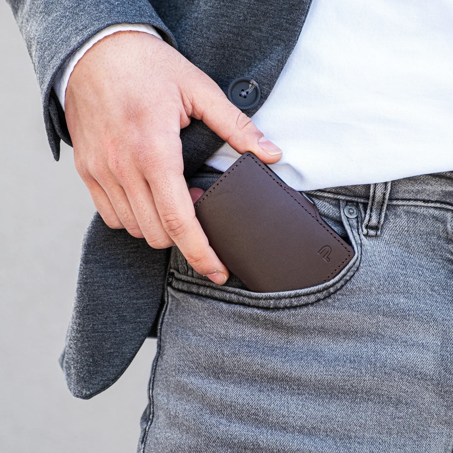 Miniwallet marrone compatto in pelle inserito nella tasca dei jeans