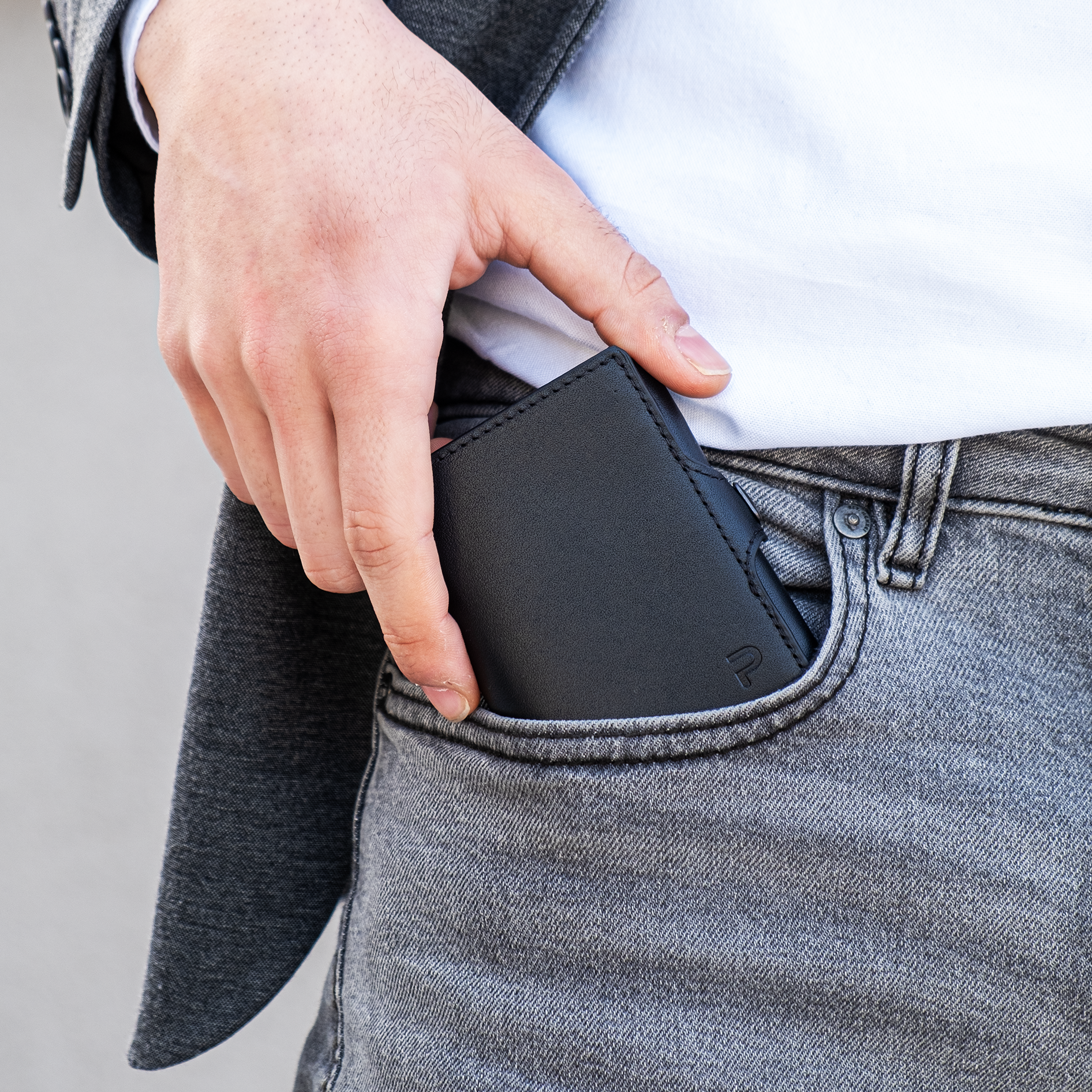Mano estrae portafoglio nero dalla tasca anteriore dei pantaloni. Sfondo elegante