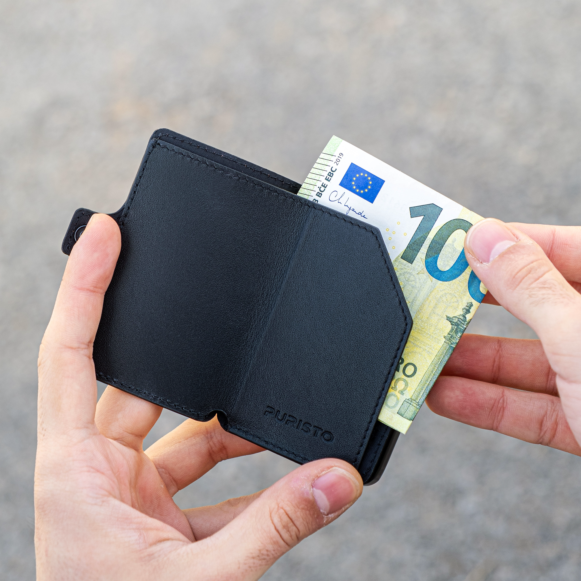 Due mani tengono un portagoglio in mano, la mano destra sfila una banconota da 100€. Sfonfo chiaro.